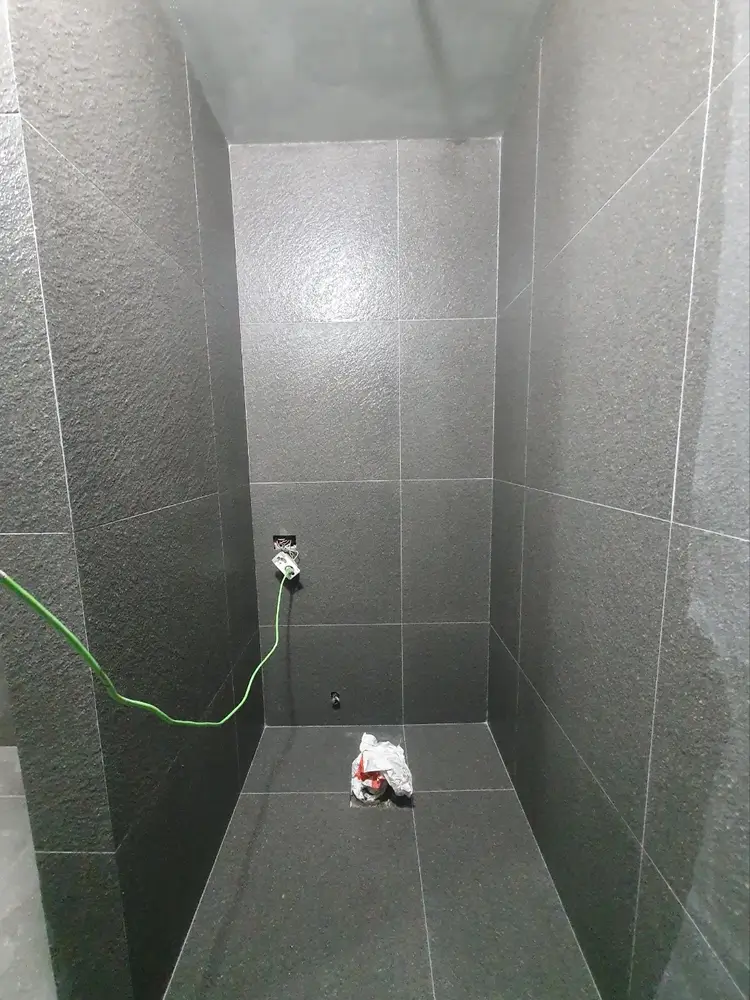 짙은 회색 타일로 마감된 샤워실 바닥 배수구